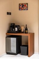Una kitchenette compacta con cafetera, un refrigerador pequeño y una botella de vino.