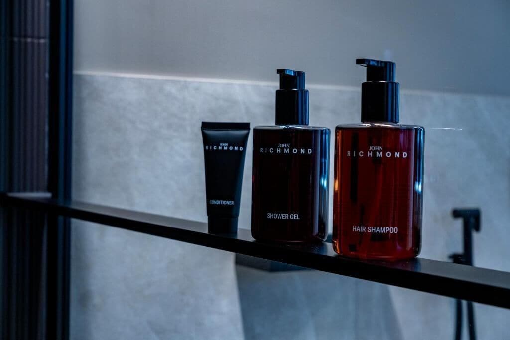 Tres botellas de productos John Richmond sobre una estantería.