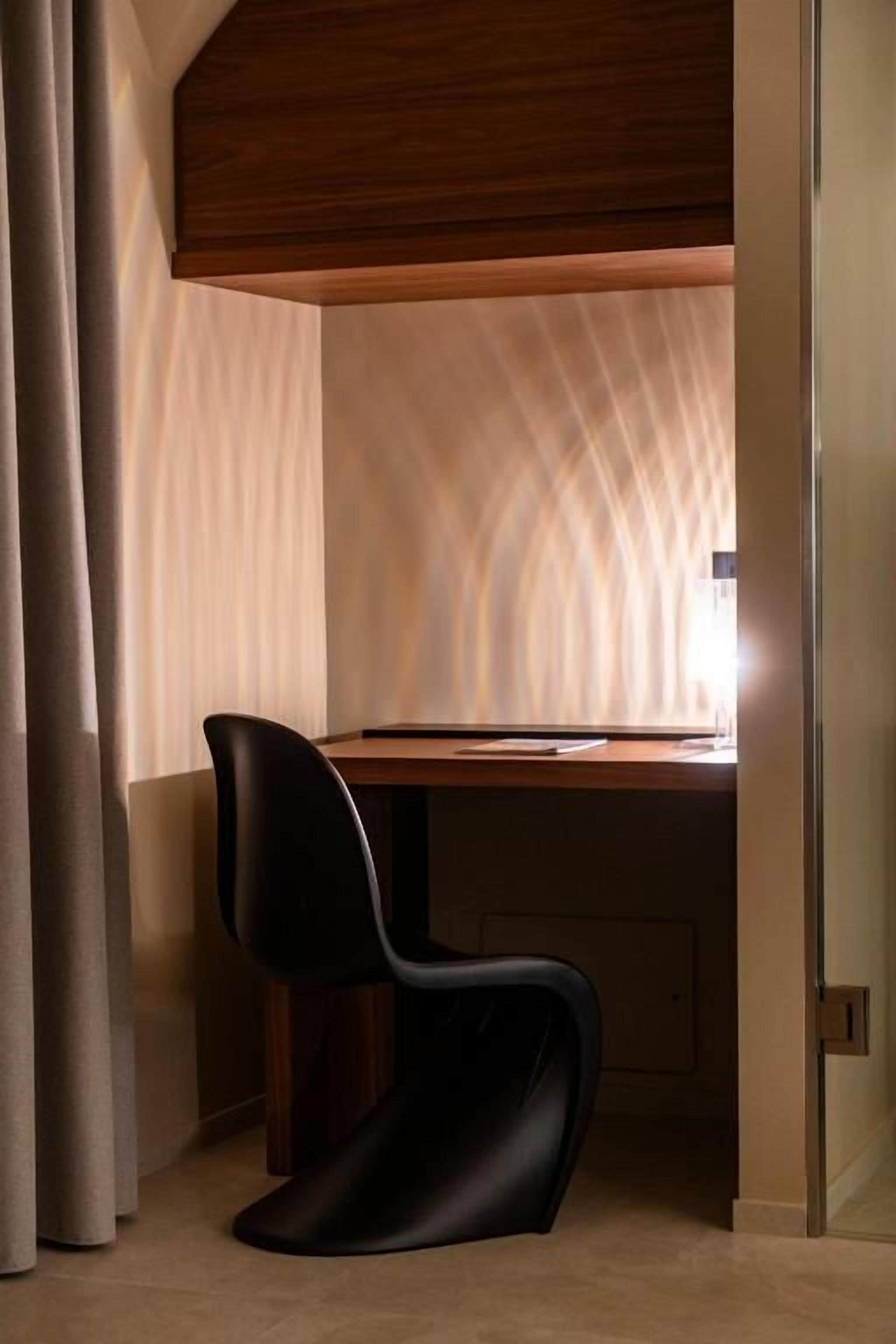 Un espace de bureau moderne avec un bureau en bois, une chaise noire et un mur à texture.