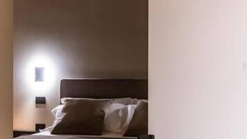 Habitación de hotel con una cama, una mesita de noche y una lámpara fijada en la pared. El número de habitación es 264.
