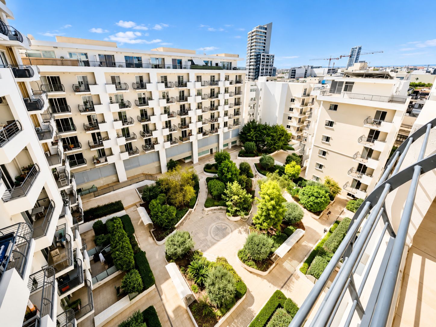 A multi-story residential building with balconies, a central courtyard with greenery, and a modern architectural design.