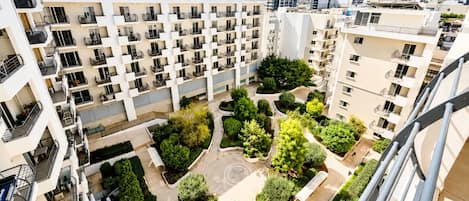 Un edificio residencial de varios pisos con balcones, un patio central con vegetación y un diseño arquitectónico moderno.