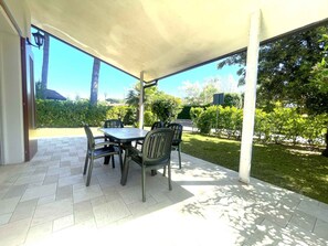 Un patio al aire libre con una mesa y sillas, rodeado de vegetación y un cielo despejado.