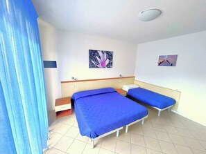 Ett hotellrum med två sängar, ett litet handfat och en taklampa.