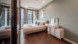 Une chambre d’hôtel moderne avec un grand lit, une table de chevet, une commode et une fenêtre avec des rideaux.