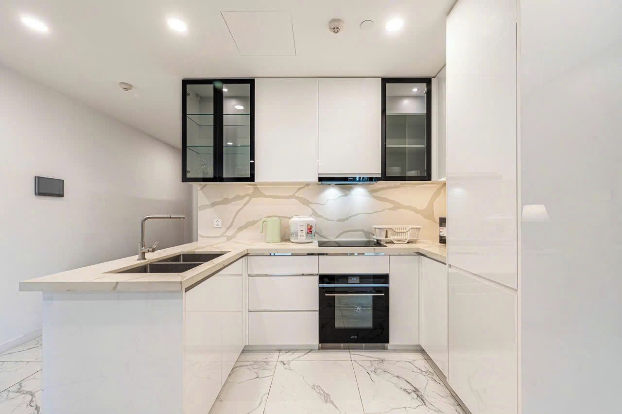 A modern kitchen with white cabinetry, a built-in oven, and a marble backsplash.