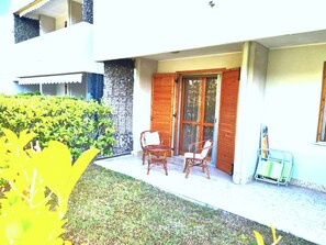 Ein Gebäude mit einer überdachten Terrasse, zwei Holzstühlen und einem kleinen Tisch.