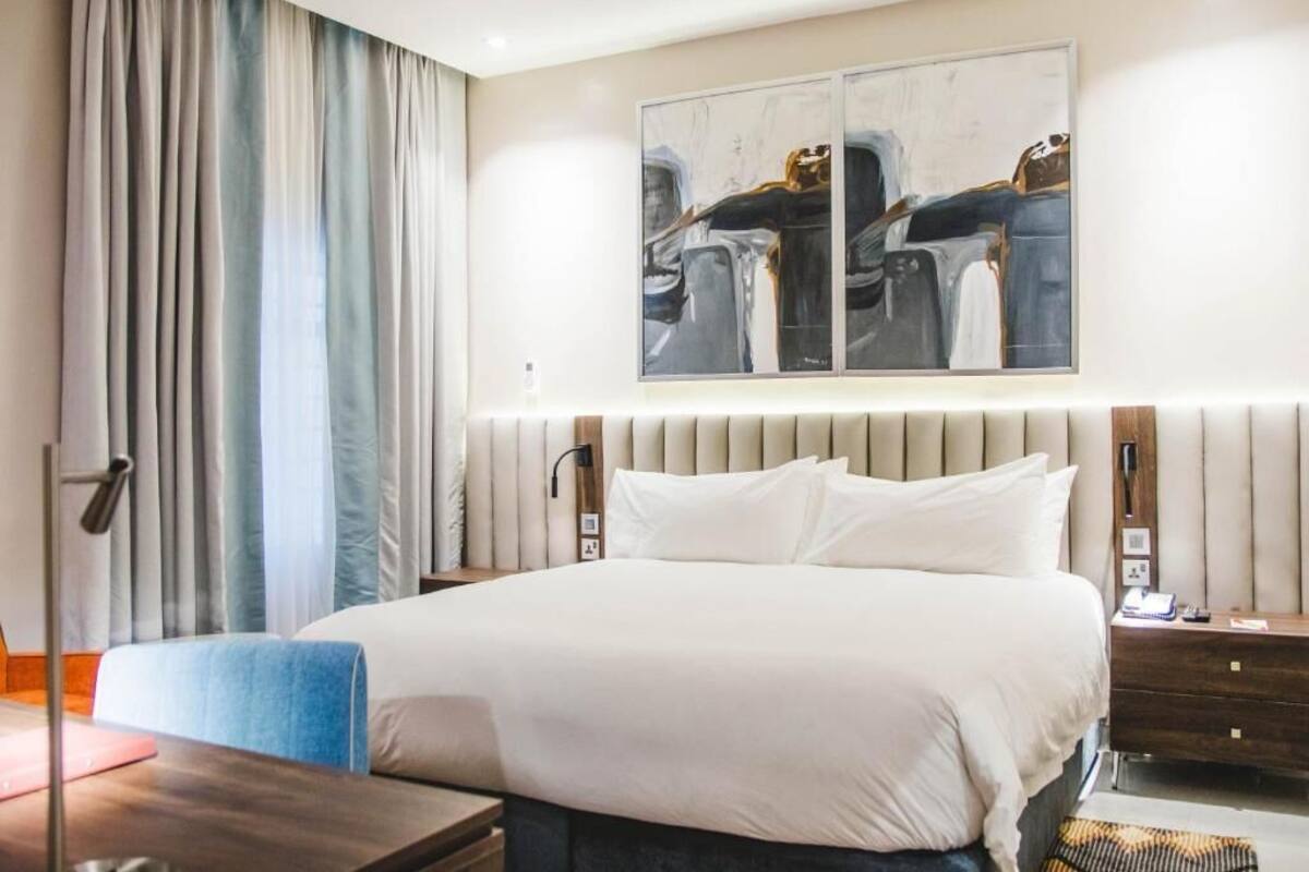 Ein Hotelzimmer mit einem großen Bett, einem Nachttisch, einer Lampe und einem Bild an der Wand.