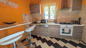 Una cocina moderna con piso a cuadros blanco y negro, armarios de madera, un microondas y una estufa a gas.