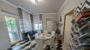 Una sala de estar con piso a cuadros blanco y negro, un sofá, una mesa de comedor con sillas y una estantería llena de libros.
