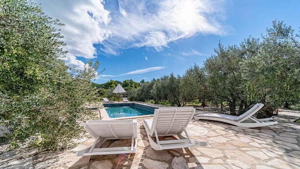 A stone pool with lounge chairs, surrounded by olive trees and a clear sky. - Holiday Home Holiday Home Ivan with Heated Pool (Blato/Insel Korčula)