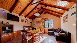 A rustic kitchen with wooden beams, a dining table with chairs, a sofa, and a TV mounted on the wall. - Holiday Home Holiday Home Ivan with Heated Pool (Blato/Insel Korčula)