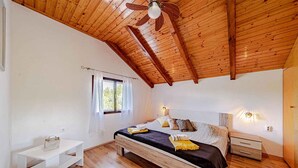 A bedroom with a wooden ceiling, a bed with a black bedspread, a bedside table, and a nightstand. - Holiday Home Holiday Home Ivan with Heated Pool (Blato/Insel Korčula)