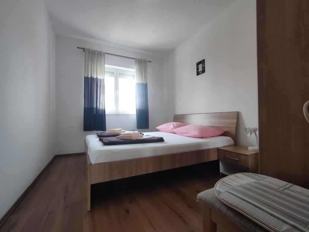 A bedroom with a wooden bed, a bedside table, a window with curtains, and a small bedside lamp.