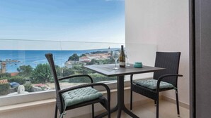 A balcony with a table and two chairs, overlooking a coastal town and the sea. - Studio VILLA STUDIO FLAT LUCE II (Krk)