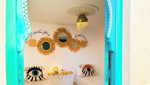 A room with a bed, a bedside table, a wall-mounted lamp, and decorative mirrors. - Porte Principale  (Marrakech)