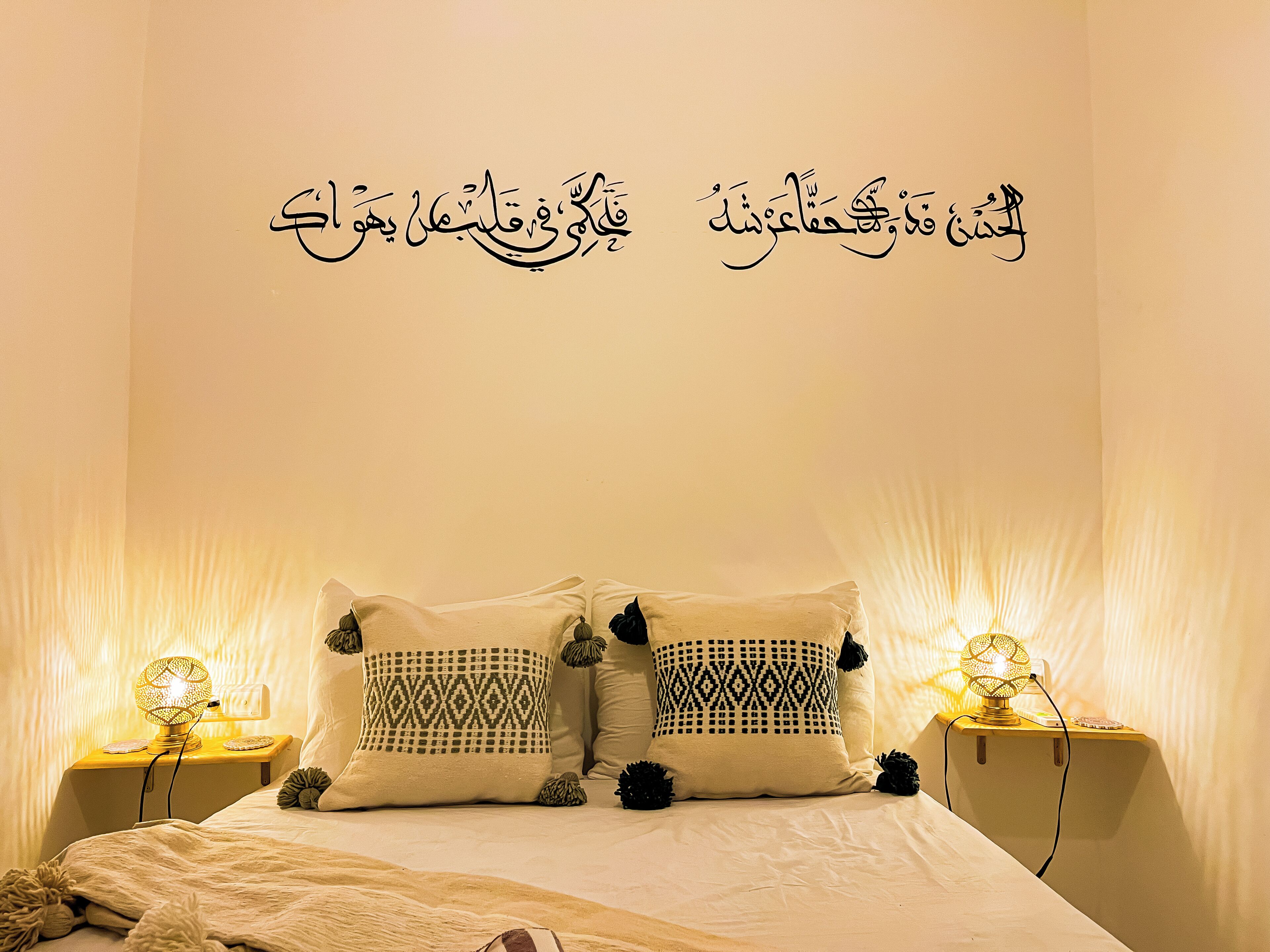 A neatly made bed with patterned pillows and two bedside lamps.