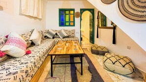 A cozy living room with a sofa, a wooden coffee table, and a patterned rug. - Porte Principale  (Marrakech)