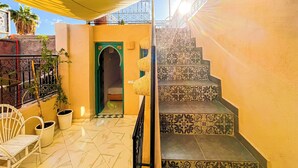 A courtyard with a staircase, a door with an arch, and potted plants. - Porte Principale  (Marrakech)