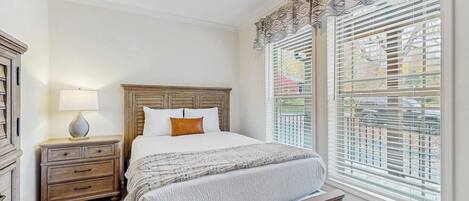 Un dormitorio con una cama de madera, una mesita de noche, una lámpara y una ventana con persianas.