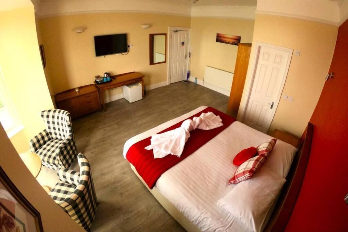 A hotel room with a bed, a desk, a chair, a television, and a door.