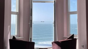 Una stanza con un letto, due poltrone e un'ampia finestra vista mare.