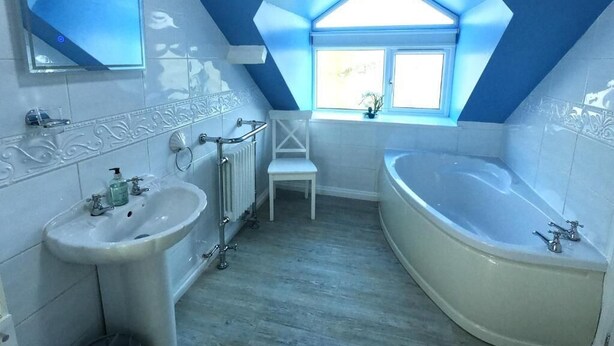 Ein Badezimmer mit Oberlicht, einer Badewanne, einem Waschbecken und einem Spiegel.