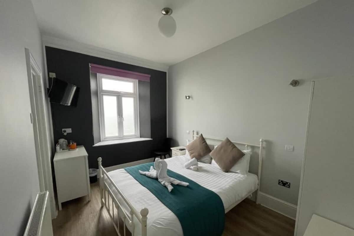 A bedroom with a bed, bedside table, and a window.