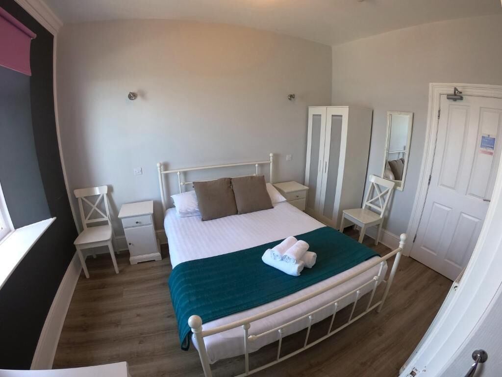 A bedroom with a bed, bedside tables, a wardrobe, and a mirror.