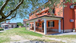 Un edificio su due piani con un portico coperto, posti a sedere all'aperto e fondamenta in pietra.
