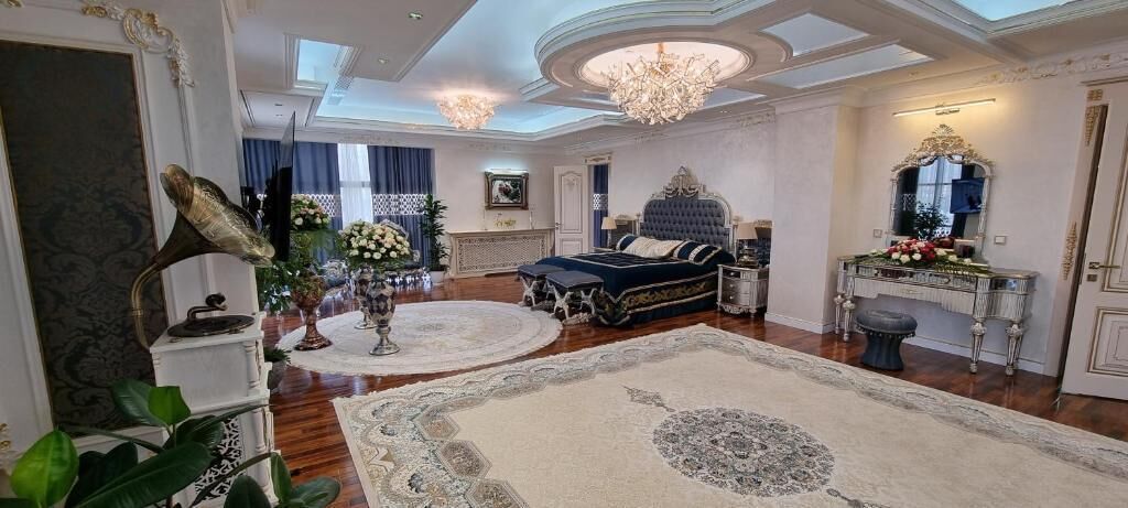 A luxurious bedroom with a large bed, ornate furniture, and a chandelier.