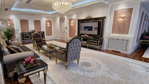Una sala de estar lujosa con un sofá, sillones, una mesa de centro y un televisor.