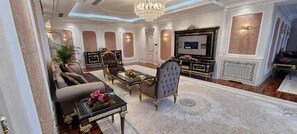 Una sala de estar lujosa con un sofá, sillones, una mesa de centro y un televisor.