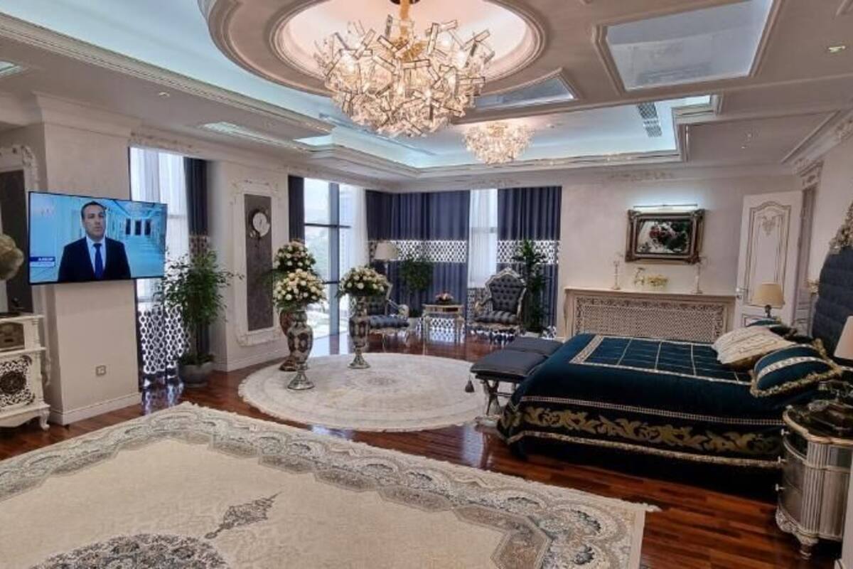A spacious living room with a large chandelier, a television, and a plush sofa.