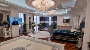 Amplia sala de estar con una gran lámpara de araña, un televisor y un sofá lujoso.