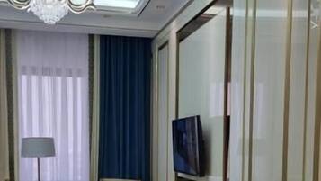 A modern bedroom with a bed, a TV, a chandelier, and a large mirror.