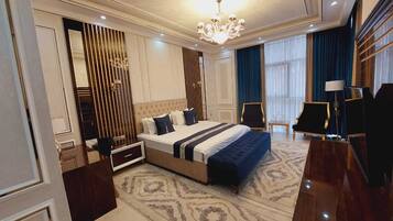 A spacious bedroom with a large bed, a chandelier, a desk, and a chair.
