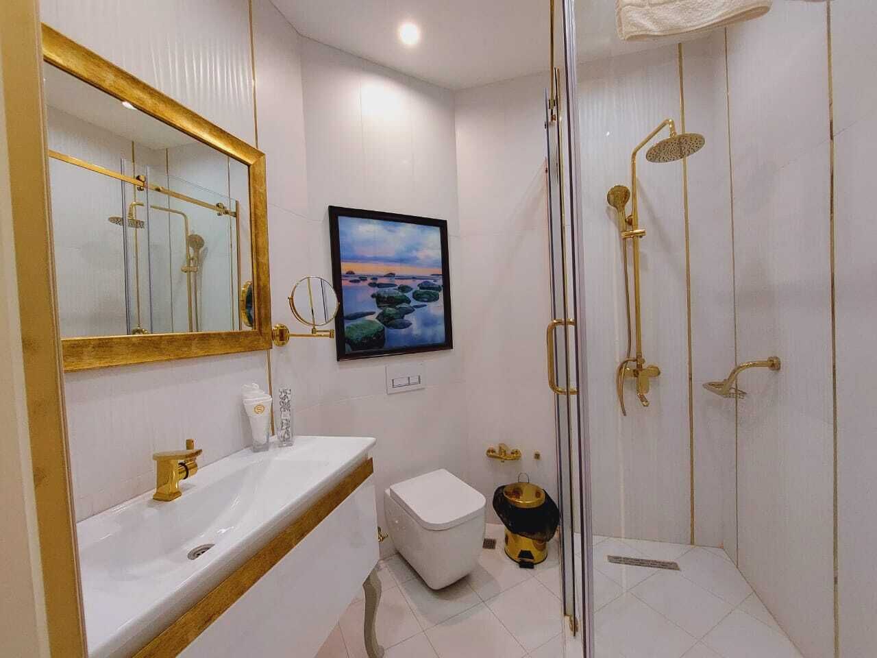 Une salle de bain moderne avec un grand miroir, un lavabo, des toilettes et un espace douche.