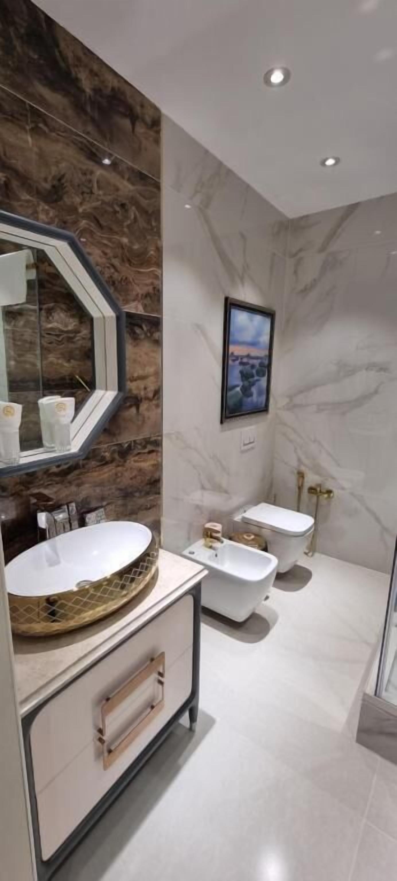 Un baño moderno con un lavamanos ovalado grande, una bañera independiente y un inodoro de pared.