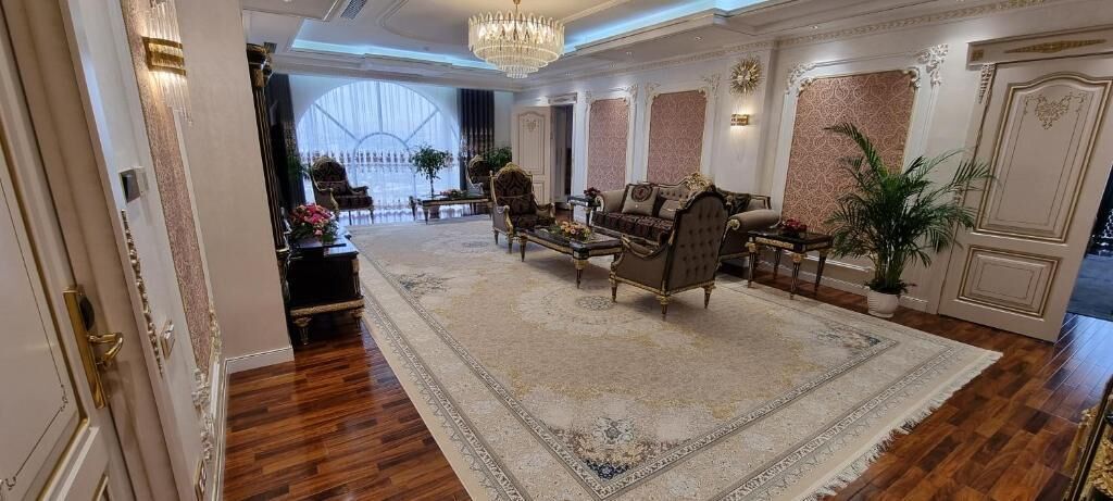 Un amplio vestíbulo con un gran y ornamentado tapiz, muebles clásicos y un candelabro.
