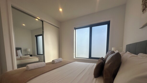 Een hotelkamer met een groot bed, een raam en een spiegel.