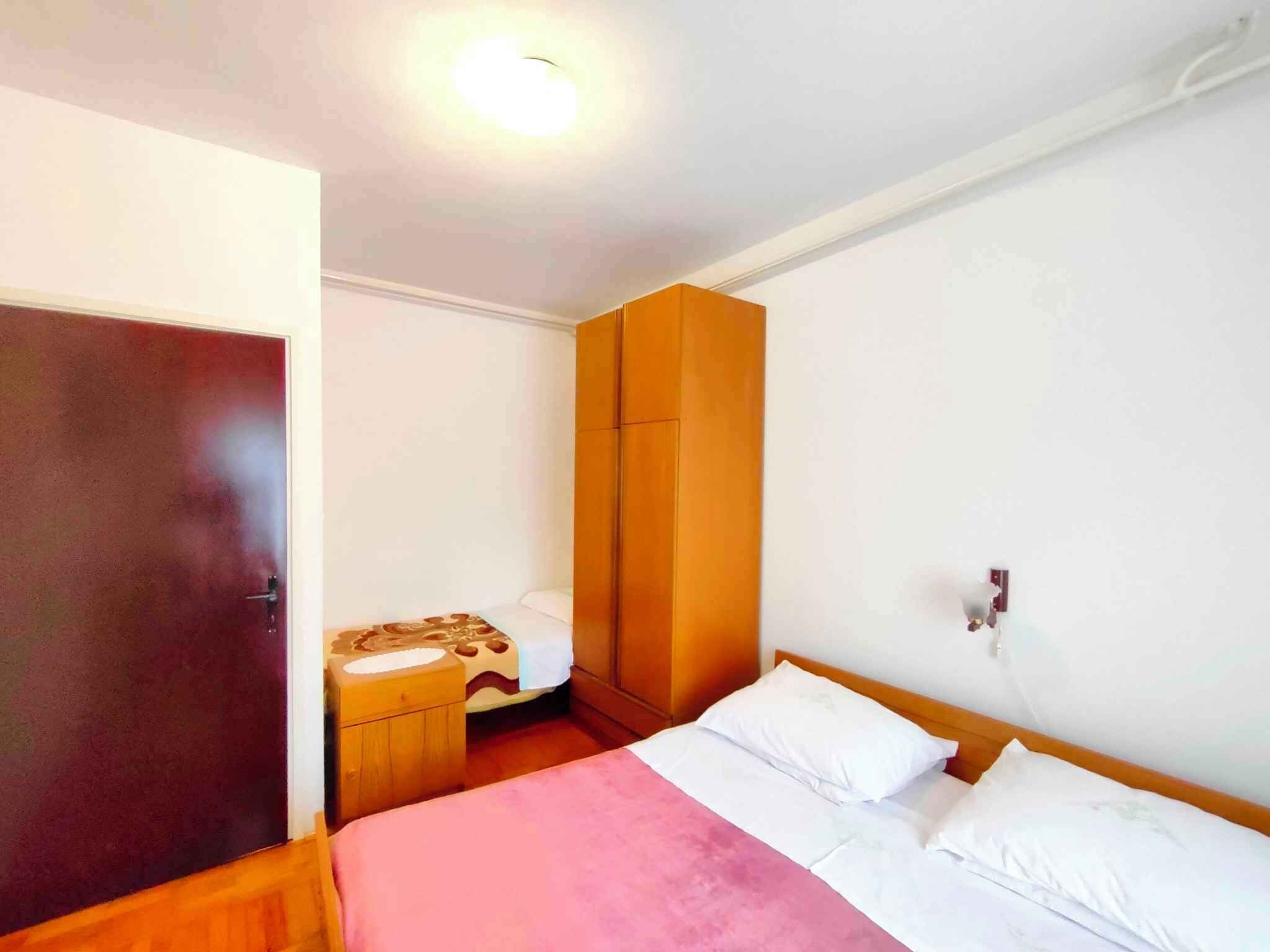 Un dormitorio con una cama, un armario de madera, una mesita de noche y una puerta.