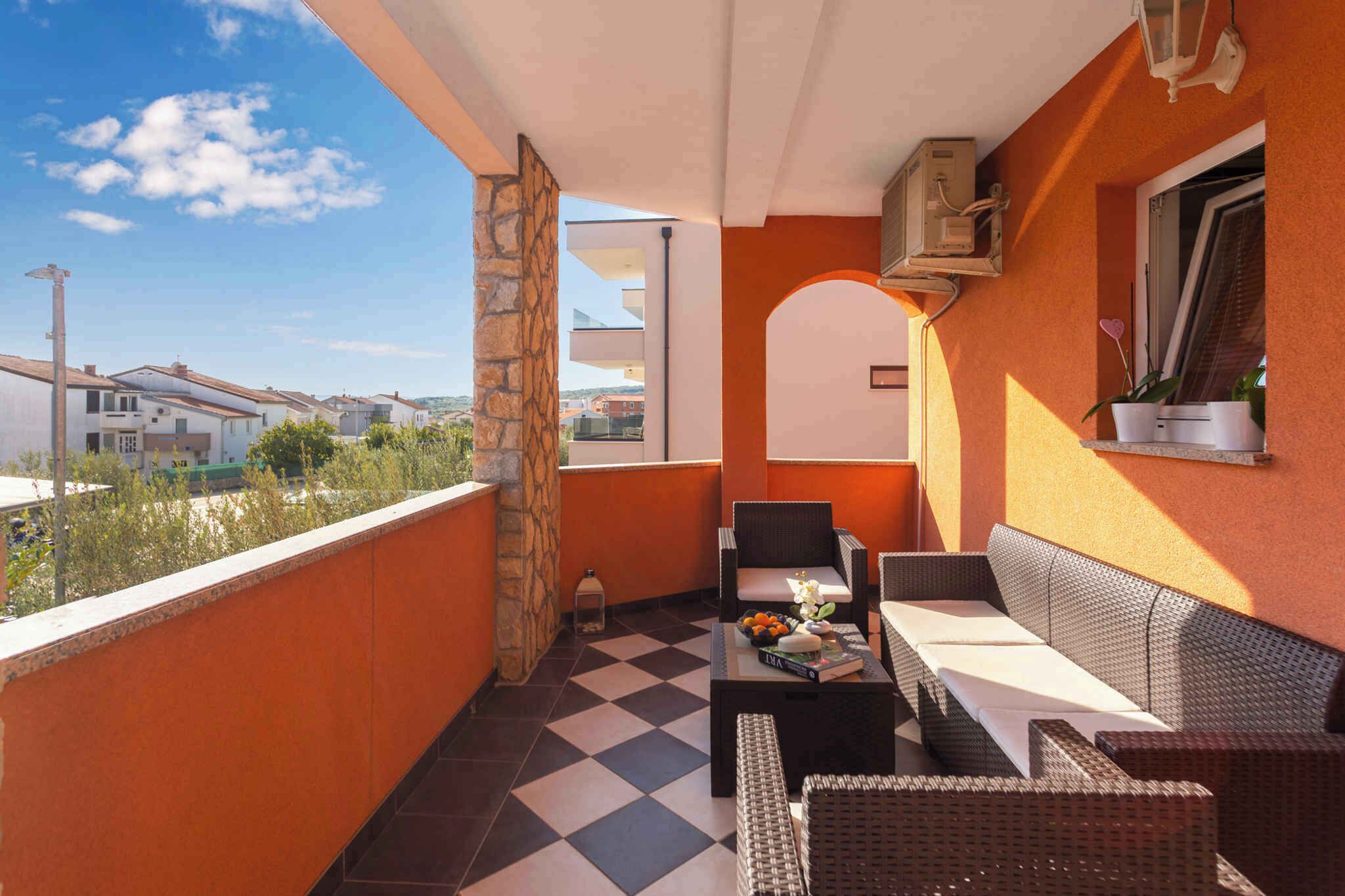 Un balcon doté de meubles en osier, d’un sol à carreaux et offrant une vue sur les maisons voisines.