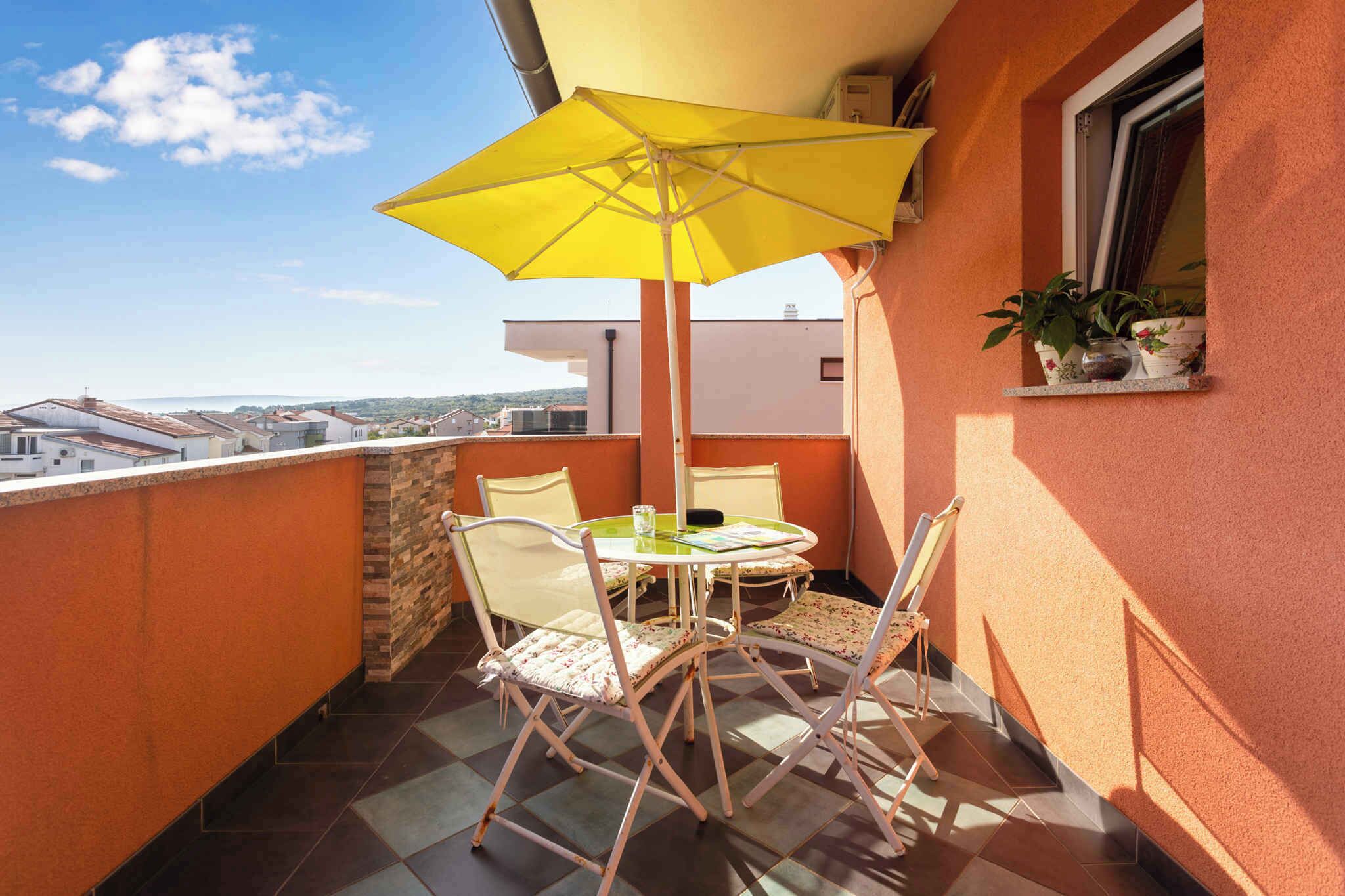 A balcony with a yellow umbrella, white chairs, and a small table.