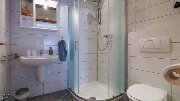 Une salle de bain avec une douche à parois de verre, un lavabo et des toilettes.