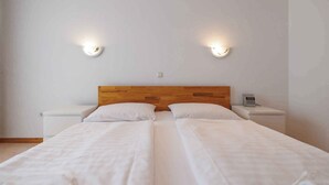 A double bed with white linens, two bedside tables, and two wall-mounted light fixtures. - Holiday Flat Guesthouse Apartment Halilagic (Krk)