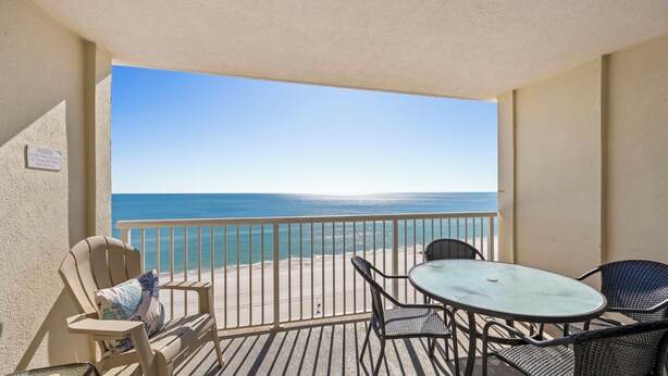 Un balcon avec vue sur l’océan, une table et deux chaises.