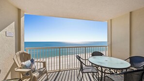 A balcony with a view of the ocean, a table, and two chairs. - Beachfront condo w/ indoor pool. Adjacent to State Park! (Gulf Shores)