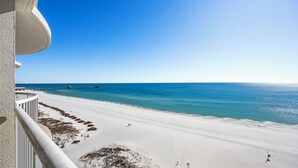 Une plage avec une jetée qui s’avance dans l’océan, un ciel dégagé et un balcon offrant une vue sur le paysage.