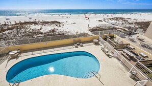 Ett poolområde med utsikt över stranden, inklusive solstolar och en pool.
